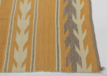 This Navajo rug was handwoven during the second quarter of the 20th century.

This Navajo rug features a warm golden fields framed by crisp stepped “arrow” or chevron bands in cream and a soft, muted purple. The alternating bands create a gentle, rhythmic movement across the textile. The palette is uncommon yet harmonious showcasing the beauty of handspun wool and classic Navajo design logic.
