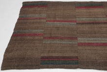 An early 20th century Dolpo blanket woven from handspun wool in the high Himalayan region of northwestern Nepal. Constructed from joined panels, the surface carries a quiet patchwork rhythm created by subtle shifts in tone and the intentional rotation of narrow striped bands.