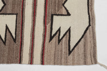 This&nbsp;Navajo rug was handwoven in the southwest United States during the 2nd quarter of the 20th century.

A beautifully balanced small-format Navajo weaving, showcasing bold symmetrical motifs rendered in a ground of hand-spun, natural wool tones. Graphic stepped&nbsp;forms float against soft variegated browns, mirror one another on each side of a classic banded center that is accentuated by&nbsp;warm red accents.
