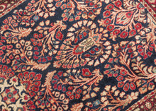 This finely woven Sarouk exemplifies the lush floral language that made the region’s carpets among the most sought-after of 1920s. Set against a deep midnight-blue ground, an intricate lattice of scrolling vines, palmettes, and rosettes unfolds with remarkable density and clarity, anchored by a subtle central medallion that gives structure to the otherwise allover composition.