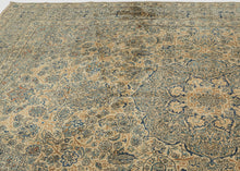 A classic faded Kerman rug with a finely articulated floral field and a soft, balanced palette of warm beige, muted blue, and gentle earth tones. The drawing is intricate yet harmonious, with scrolling vines and rosettes arranged around a calm central medallion that gives the composition focus without heaviness.