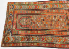Antique Kuba prayer rug with a geometric mihrab arch and a densely patterned field of small colorful boteh motifs, framed by multiple angular borders in coral, ivory, and green tones.