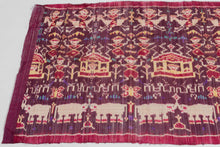 A striking Cambodian&nbsp;hol textile woven in the weft ikat technique, dating to the 1980s revival period. Against a rich plum and magenta ground, the composition features mirrored rows of apsara or court-dancer figures, stylized Angkorian temple forms, floral motifs, and bands of Khmer script identified as reading “Kampuchea.”

The imagery draws on Cambodia’s deeply rooted Angkorian visual language, translating forms associated with temple architecture and celestial dancers into silk. Rather than depictin