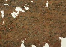 A remarkably understated Coptic textile fragment, woven on a warm brown linen ground and patterned with repeated horizontal bands of small linked motifs in deep blue-green, with traces of red.

Rather than the bold tapestry panels more often associated with Coptic textiles, this piece has an appealingly spare, almost minimalist quality. The repeating forms create a quiet rhythm across the surface, their irregularities revealing the hand of the weaver.
