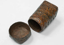 A finely made lidded basket attributed to the Kuba peoples of the Democratic Republic of the Congo, constructed from broad strips of plant fiber in a tightly worked herringbone plait.

The tall, compact form is animated by a bold chevron pattern that shifts direction across the surface, giving the basket a distinctly architectural quality. The fitted lid continues the same interlocking weave, creating a unified sculptural form when closed.