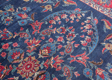 An elegant vintage Tabriz carpet distinguished by its unusually deep indigo-blue field and spacious floral drawing. A softly articulated central medallion anchors the composition, surrounded by scrolling vines, palmettes, blossoms and delicate boteh rendered in saturated shades of cornflower and sky blue, rose, coral, red, celadon, camel and ivory.