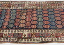 A wonderfully graphic Kurdish rug with a dark indigo field densely packed with rows of large botehs in coral, salmon, blue, green, ivory, and soft brown. Each boteh is filled with fine horizontal patterning, creating a lively surface of shifting color and texture.