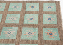 A wonderfully graphic vintage latch-hook rug with a repeating grid of aqua panels, each centered by a playful abstract motif in soft blush, salmon, and deep blue. The warm brown ground gives the composition structure while allowing the almost cellular, biomorphic forms to float across the surface.