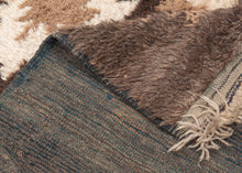 A wonderfully tactile Angora Tulu rug distinguished by its exceptionally soft, shaggy pile and striking geometric composition. Woven in a restrained palette of undyed Angora goat hair, the rug features a rich, earthy field of charcoal brown and warm taupe, punctuated by an ivory central medallion with jagged, irregular contours.