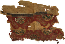 An exceptionally early Coptic textile fragment, woven more than 1,400 years ago, preserving richly patterned tapestry bands against a warm linen ground. Deep red fields are animated with scrolling vegetal forms and inset medallions containing highly stylized floral, animal, and possibly scarab-like motifs in ochre, green, cream, and dark brown.