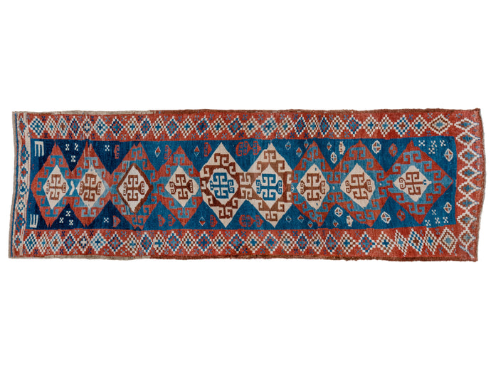 This runner was woven by Kurds in Eastern Anatolia during the second quarter of the 20th century. It features a pattern of wonky interconnected diamonds on a glowing blue ground and framed by a border of simpler diamonds on a red ground. The simple but effective palette also utilizes brown and white tones as well as a few moments of pale yellow