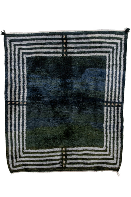 This modern rug combines tight handmade moroccan shag with Deco aesthetics. An open field is framed by concentric squares with a break at each cardinal point. The field is mesmerizing shifting from greens to blues in waves much like an oil slick.