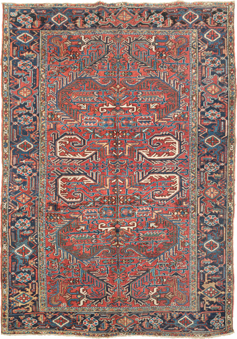 This All Over Red Heriz features an allover design of scrolling leaves in tones of navy,indigo, yellow, green, gold and ivory on a patinated red ground. All-over designs are less common on Heriz rugs which most often feature large central medallions. The main border is composed of alternating rosettes and palmettes utilizing the same tones as the field on a navy ground