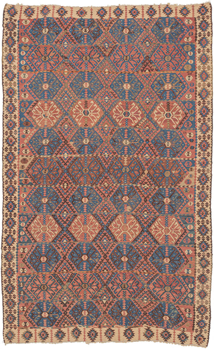 This Kagizman kilim was woven in Eastern Anatolia during the second quarter of the 20th century.  It features a repeat field of crisply rendered latch-hooked devices that alternate with diamond forms in tight formation in patinated reds, blues, ivory, and gold. Small rounded protection symbols fill the sides of the field leaving little empty space. Nicely framed by jagged burr-like devices on an ivory ground.