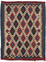 This kilim was woven in the Caucasus during the late 19th century.  It features a field of stepped polygons and small diamonds in various shades of red and blue on a bright ivory ground. The pattern can be viewed in multiple way and the navy diamonds also form a central diamond. The ivory field is framed by jagged purple zigzags on the sides and polychrome triangles 