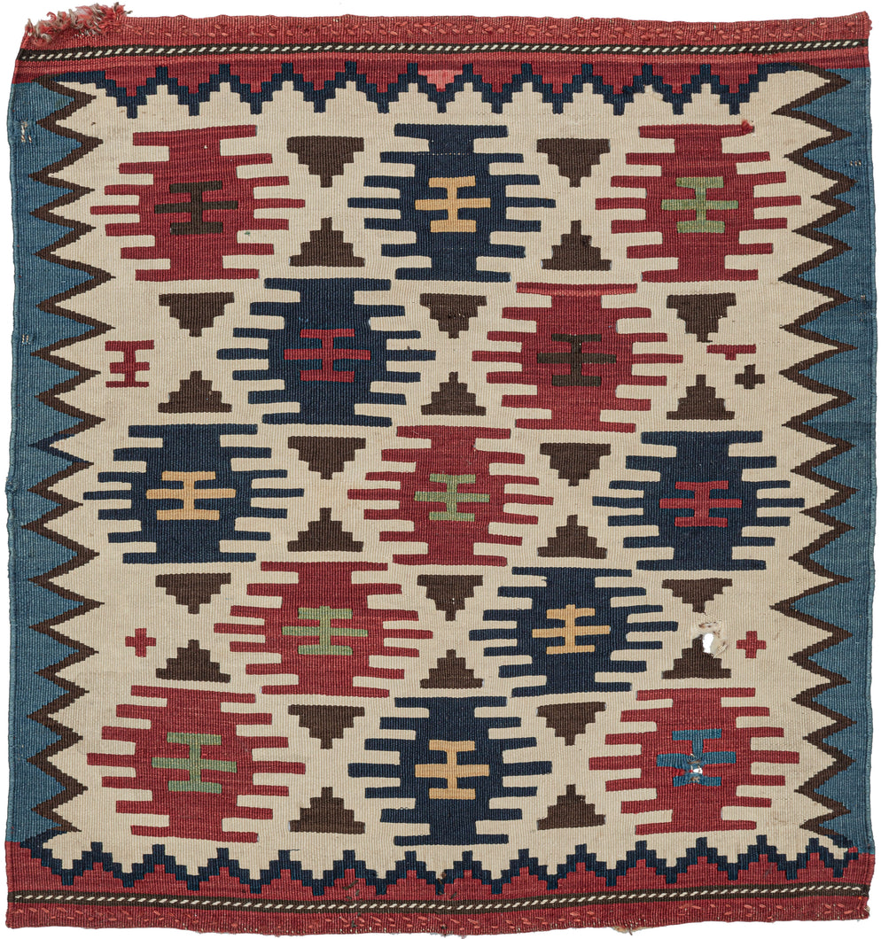 It features a field of red and blue stepped polygons and small brown triangles in various on a bright ivory ground.  The ivory field is framed by jagged zigzags around the perimeter and finished with thick bands of blue and red on the sides and ends respectively. May have been made as one side of a saddle bag. A small but impactful piece.