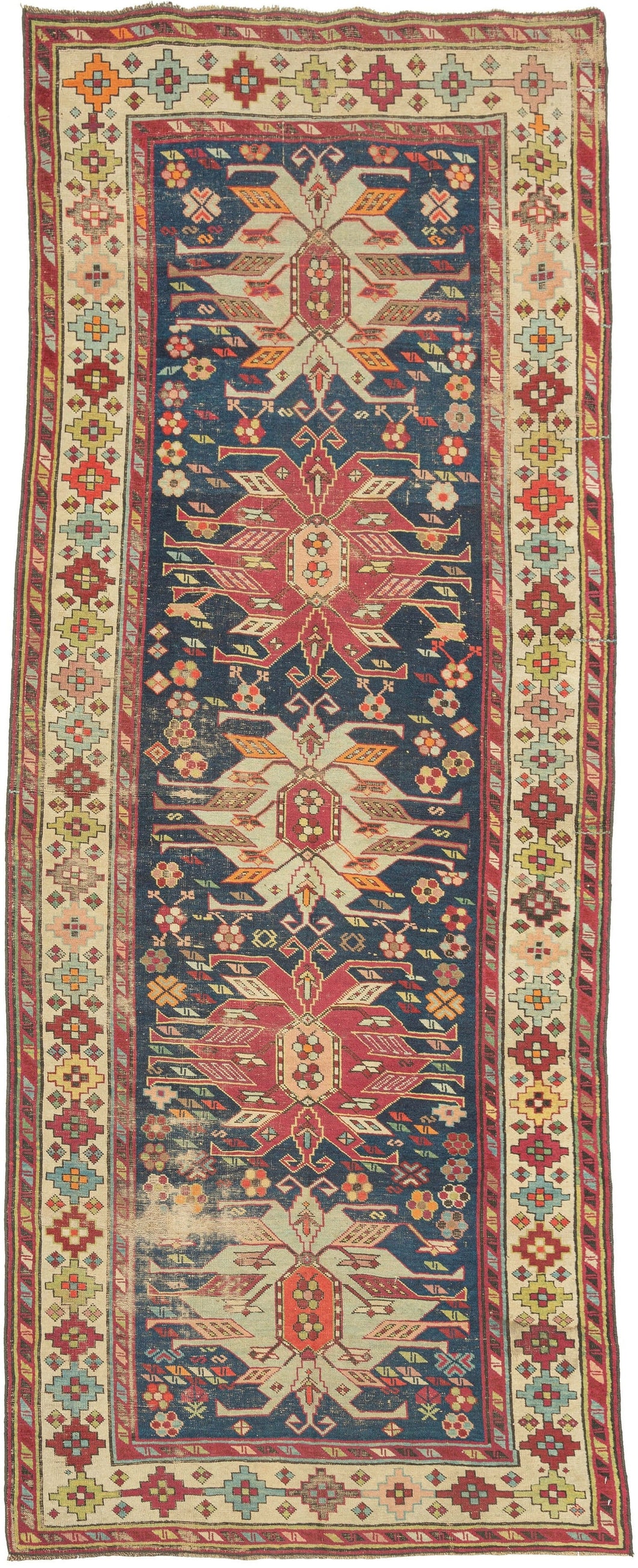 rug woven in the Karabagh region of the South Caucasus during the late 19th century. pattern of energetic palmettes that alternate between icey blue and magenta small rosettes scattered about like a field of colorful wildflowers. Karabagh weaving and achieved with cochineal, an insect derived dye. stepped polygon shaped rosettes in a wild array of tones including oranges, greens, pinks, blues, yellow and brown atop a bright ivory ground