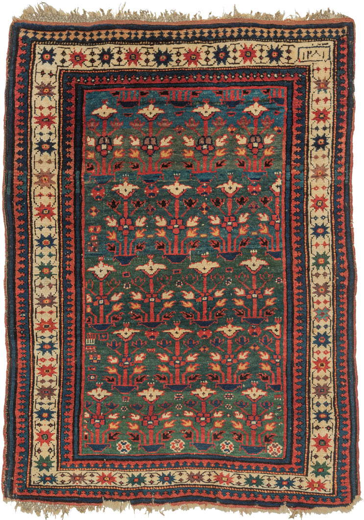 This rug was woven in the South Caucasus in or around the Karabagh region and is dated as 1281 Hijri or 1864 in the Gregorian calendar. 

It features a rare and poetic allover design of stylized floral shrubs ngrowing from pots and evoking themes of paradise gardens. The uncommon and desirable rich green ground shifts in tone from hunter green to forest green and finally a sublime sapphire blue. The overall rhythm is visually arresting—layered yet orderly, with fine asymmetrical details that animate th
