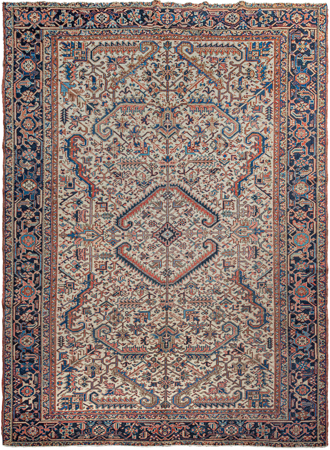Antique Heriz rug featuring a graphic all-over design of geometric rosettes and sawtoothed serrated leaves in blues, reds, yellow and soft pink on a rare ivory ground. Although the design is all-over as opposed to the classic Heriz central-medallion motif, the compelling leaves draw the eyes to the center.  The main border is composed of a reciprocating palmette design showcasing various well-executed blue tones that frame the ivory field perfectly.