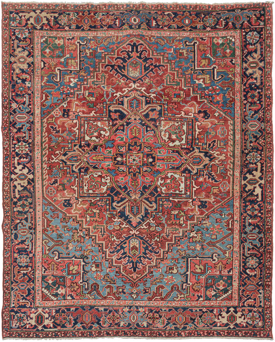Heriz rug features a geometric central medallion and rich saturated tones . A brick-red field is complemented by the deep navy, french blue, yellow, and coral tones with brown and ivory accents. The four french blue cornices invigorate the rug and a wonderful undulating abrash adds layers to the composition. It is framed by a navy main border of polychrome palmettes. In a desirable size that is more squarish than usual.