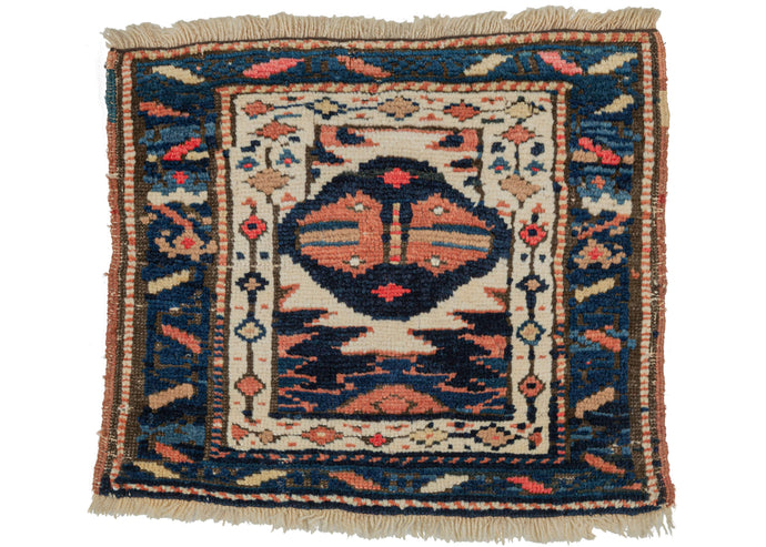 Antique Karadja small pile weaving featuring a medallion that strongly resembles a face, it is perfect as a small wall hanging or bedside rug. Has strong indigo blues, soft oranges, and soothing ivory colors.