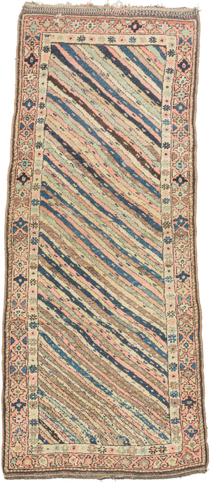 This rug was handwoven by Kurds during the first quarter of the quarter of the 20th century.    It features a traditional Kurdish design of diagonal stripes in a rainbow of pastel tones. The seemingly random color placement along wiht the varying thickness and movement of the stripes imbibe the rug with life and movement. Framed by a main border of stepped polygons and triangles on a coral ground with ends that are beautifully embellished with multiple barber pole weft floats.