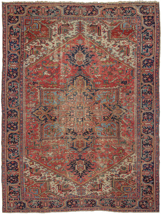 Antique Heriz rug featuring a geometric central medallion on a madder red ground. The four cornices mirror the design of the medallion in a different color combination. Dark navy, turquoise, gold, pink, ivory, and two distinctive greens round out the palette. The main border is composed of blossoming palmettes on thick and visually interesting meandering vines. The main border is flanked by minor borders that feature complementary floral meanders.