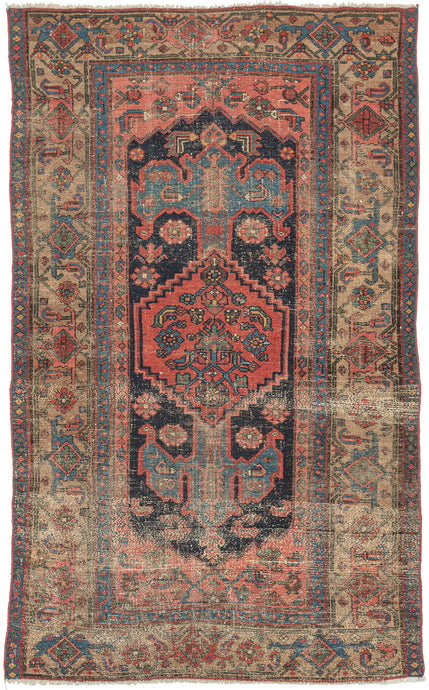 This Kurdish rug was handwoven during the early 20th century in Northwest Iran.  It features a soft red central medallion floating atop an open midnight blue field. A variation of the herati design can be found in both the medallion and the coral cornices. The meandering palmette border sits on a camel ground and is framed by two thin blue minor borders.