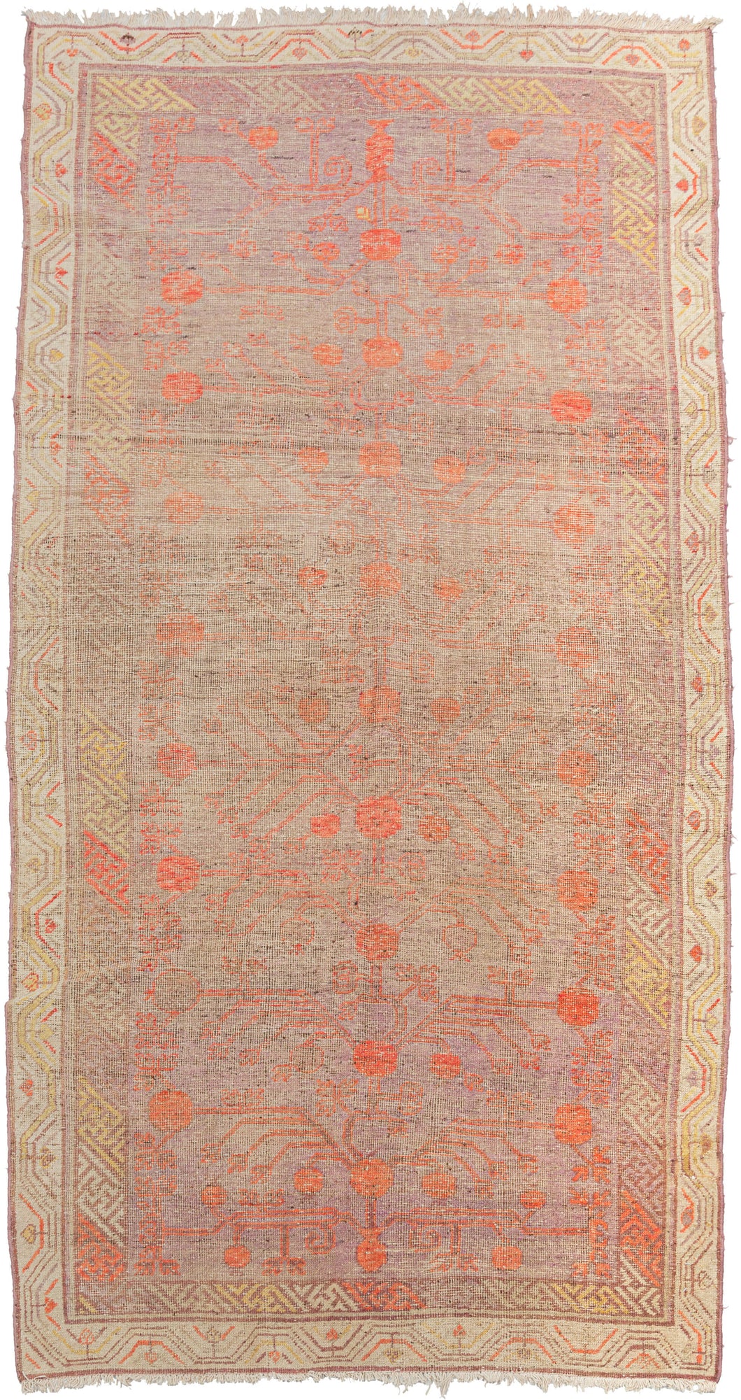 This Khotan rug was woven in Northwest China, which is also known as East Turkestan, during the early 20th century.   red pomegranates on a faded grayish purple ground.  It showcases classic Khotan patterning which is a wonderful hybrid of both Central and Eastern Asian design with the East Asian greek-key interior border which blends right into the field and the ivory exterior border similar to those found in Central Asian Turkmen rugs. 