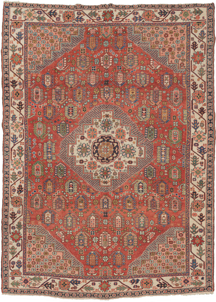 This Rare & Unusual Heriz features a stepped central medallion with a large central rosette surrounded by smaller rosettes atop a rich red ground of large botehs. Hatchmarks around the medallion as well as the stepped cornices give the piece a dynamic energy.  Each cornice features a field of rosettes on a coral ground. The main border is composed of a crisply drawn rosette meander on a bright ivory ground. Many of the classic Heriz hallmarks are in rare patterns and sizes.