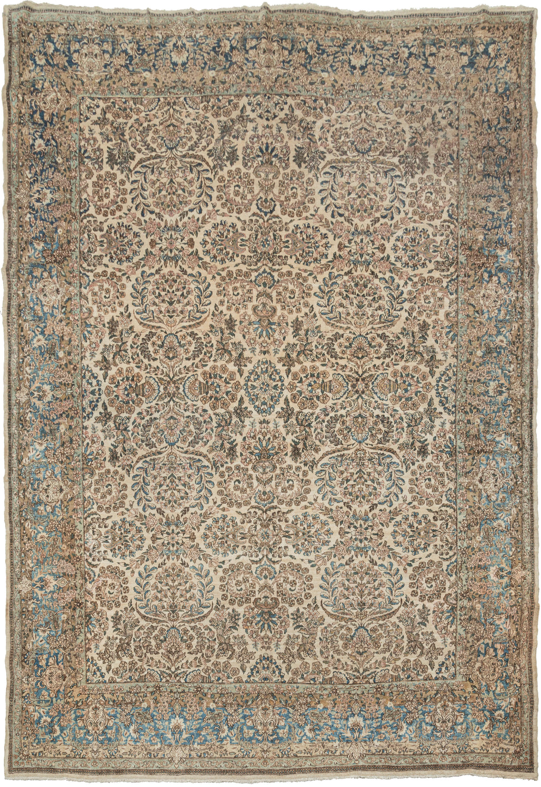 Kerman rug handwoven during the second quarter of the 20th century.  It features an allover design of bouquets and floral sprays in soft tones of pinks, blues and browns on a creamy ivory ground. It is framed by a perfectly reconciled border of blossoming flowers on a light blue ground. Precisely rendered to great visual effect with a soft palette for an understated yet elegant feel.