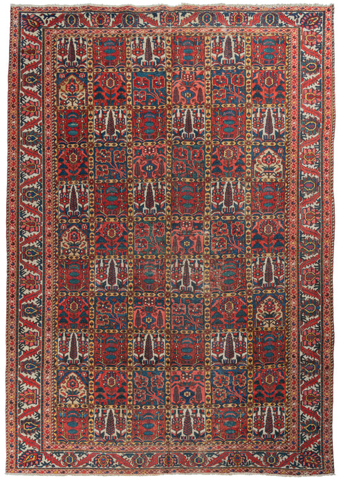 Mid century Bakhtiari Garden rug featuring a classic garden design in madder reds, indigo blues, and soft yellows, browns, and ivories. A shrub, flower or tree appears in each square with an alternating repeating pattern. The reconciled main border showcases blue and salmon palmettes and serrated leaves on an ivory ground.