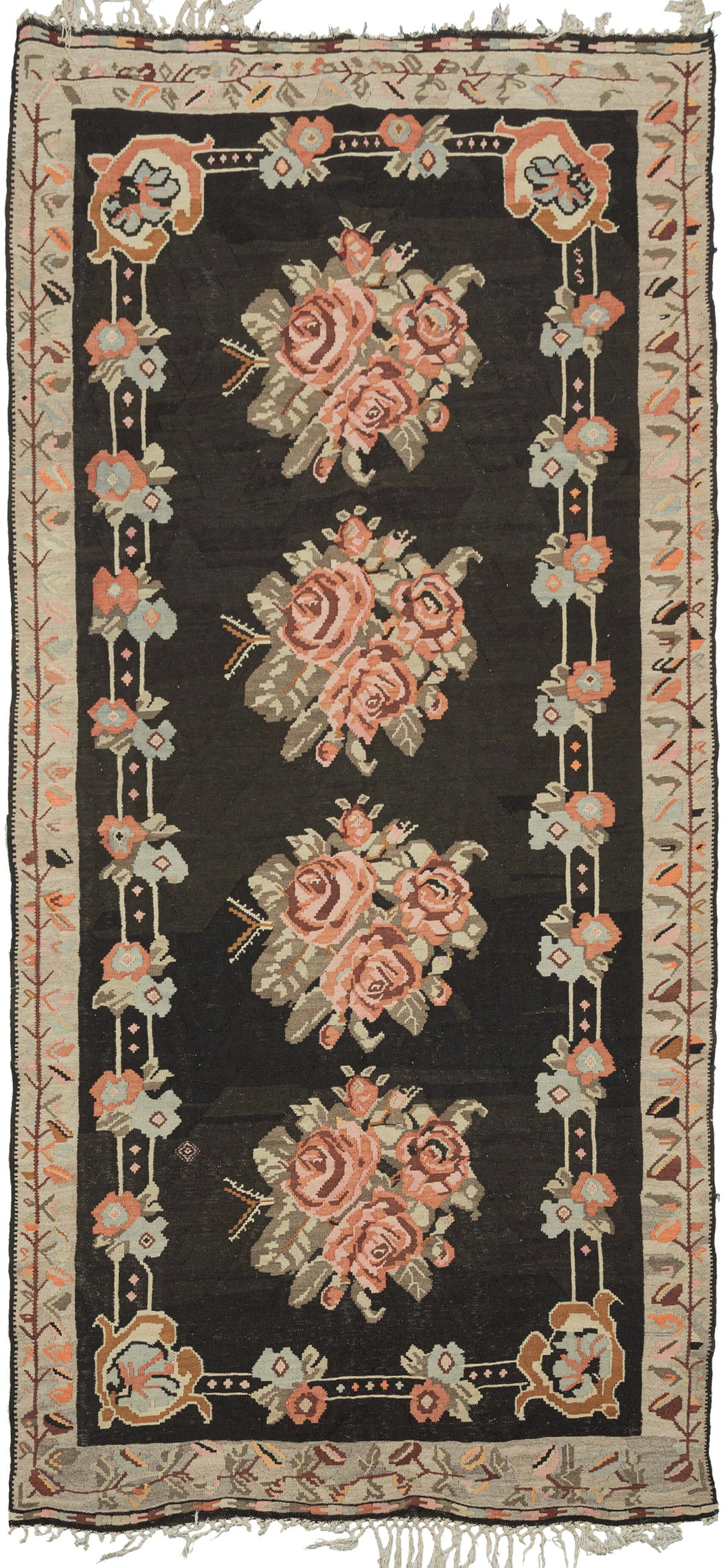 This Bessarabian kilim features four bouquets plush cabbage roses in maroon, orange and soft pink on a deep brown, almost black field. It has a small inner frame of pairs of simpler flowers on a track with c scroll cornices. The proper outer border features a scrolling view with various leaves in bright oranges, slate and soft pinks on a camel ground. 