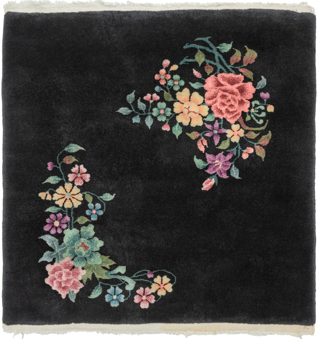 This Art Deco rug was handwoven in Tientsin, China during the second quarter of the 20th century.   This sumptuous Deco rug features a detailed naturalistic design of two distinct blossoming branches on a black ground. The eye-catching design features peonies, chrysanthemums, fruit blossoms among flowers rendered in greens, orange, pink, blue and purple. The flowers really pop against the true black ground.