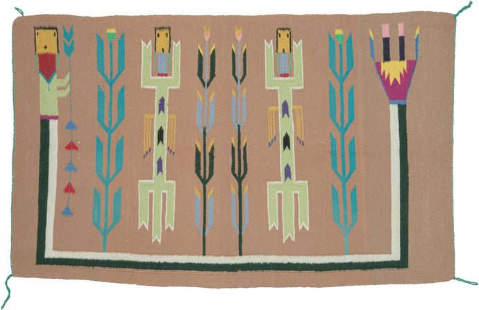 This Mid Century Yei Navajo Rug features two figures alternating with corn stalks in a row, surrounded by a Rainbow Guardian on three sides in a ceremonial-themed design  A bright and cheerful color palette of black, white, yellow, pink, purple, teal sage, and periwinkle pop against a sandy brown ground.