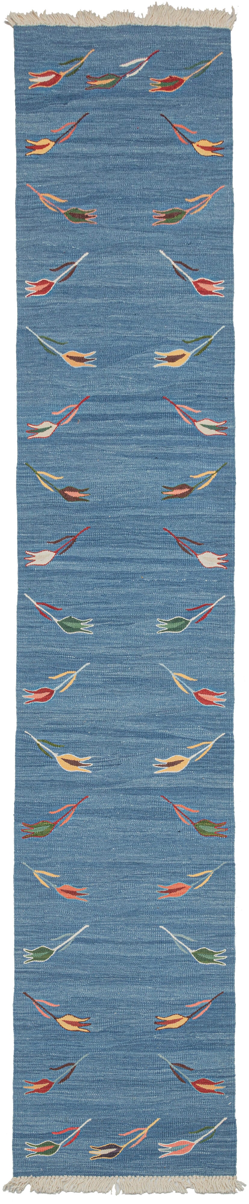 Blue tulip motif kilim runner featuring a repetition of delicate polychrome tulips around a blue field. The tulips are finely woven of handspun wool in naturally dyed tones of yellow, green, brown, red, and pink and float upon an indigo field. The indigo background vibrates with each natural variation giving it a simple and straightforward presence, as well as a special feeling.