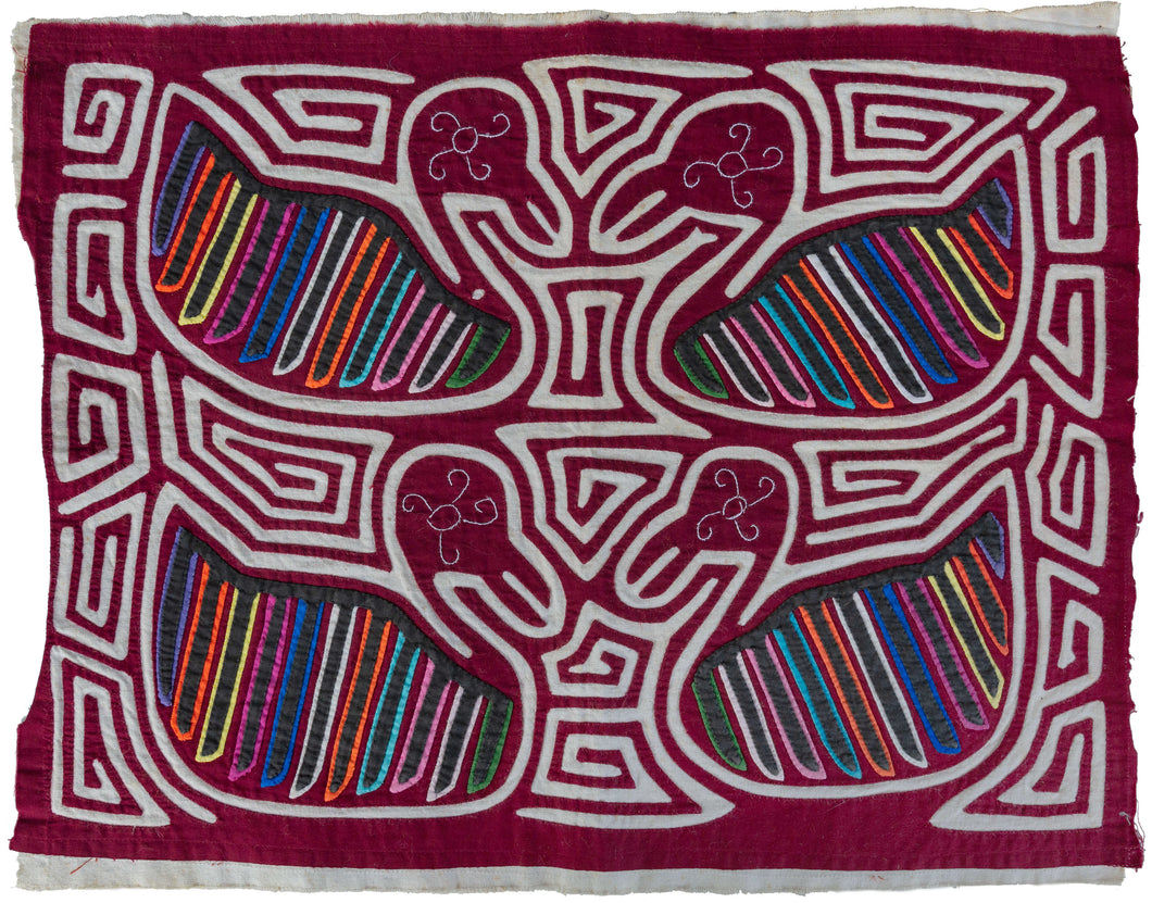 Vintage Mola cloth handmade by the Guna (previously spelled Kuna) people of Panama. Mola is a reverse appliqué technique, similar to the technique used in quilting but using multiple layers of different-colored cloth that are first sewn together before a design is creating by cutting away different layers. This Mola features two sets of confronting birds amongst a scrolling maze-like backdrop.