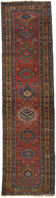 Karadja runner featuring a pattern of alternating geometric shapes and hooked lozenges on a rich red ground. Indigo blues, sage green, gold, ivory, and caramel provide a well-balanced palette a give the runner a professorial air.