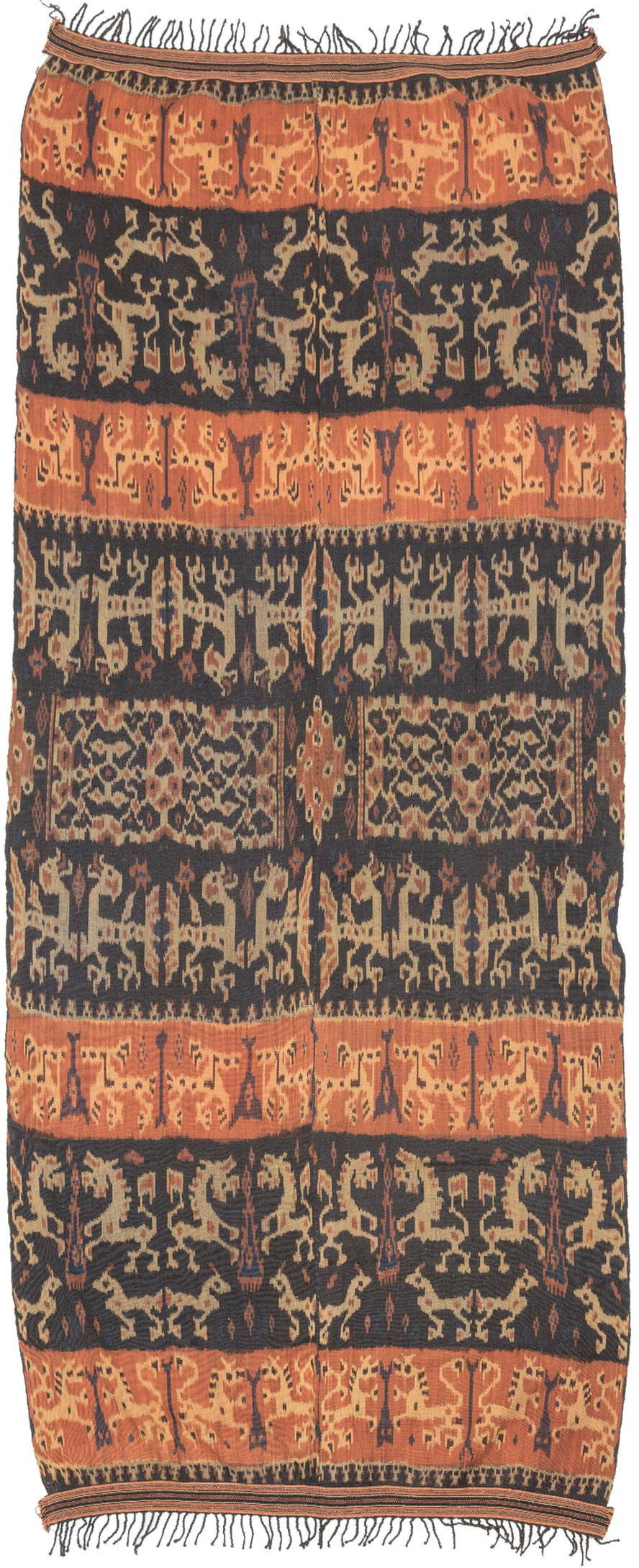 An Indonesian cotton ikat from Sumba with contrasting horizontal bands of deep indigo and warm rust. Stylized animal and ancestral motifs emerge rhythmically across the dark ground, their forms softened by the characteristic feathered edges of the resist-dye technique.