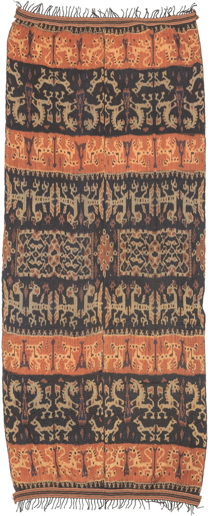 An Indonesian cotton ikat from Sumba with contrasting horizontal bands of deep indigo and warm rust. Stylized animal and ancestral motifs emerge rhythmically across the dark ground, their forms softened by the characteristic feathered edges of the resist-dye technique.