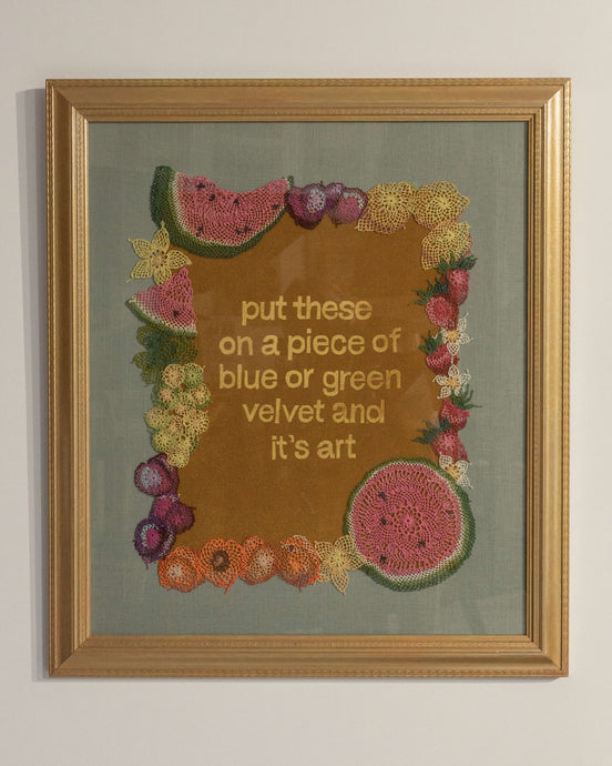 Gold velvet embossed with the words “put these on a piece of blue or green velvet and it’s art” surrounded by a frame of colorful fruit and blossoms made in Armenian needlelace, including watermelons, plums, lemons, strawberries, apricots, and grapes.