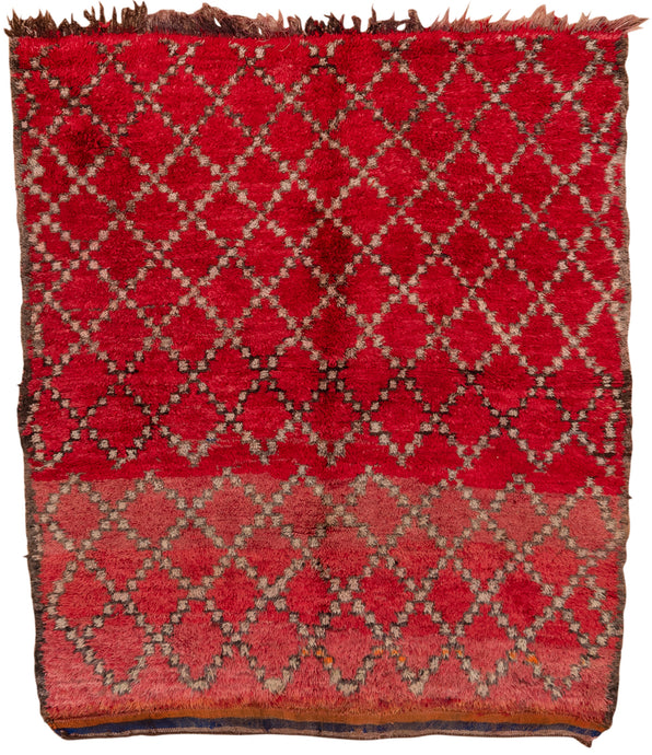 This Marmoucha rug was woven in the Middle Atlas mountains during the 20th century.  It features a diamond lattice design in black and gray on dramatic red ground.  that appears solid at first glance but with very nuanced shifts in tone. The lattice breaks near the center adding interest and individualism to the piece. Small moments of isolated orange have a similar effect. In a rare squarish size.