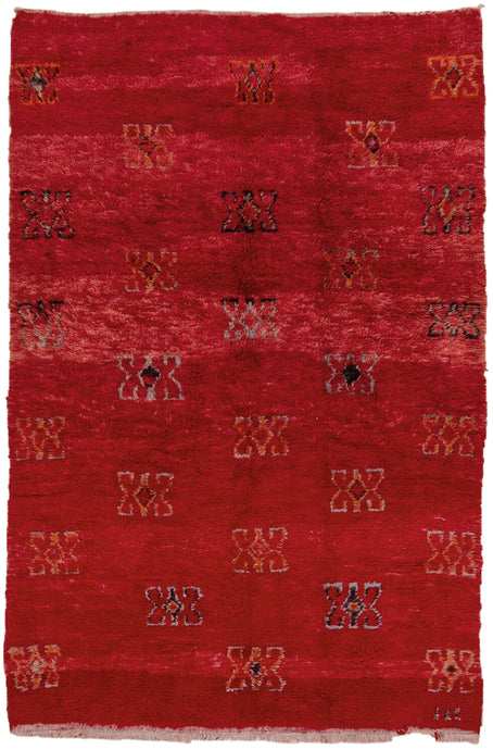 This Moroccan rug was woven in the Middle Atlas mountains during the 20th century.  It features a powerful variegated red ground full of large butterfly-esque protection symbols in black, orange and purple. 