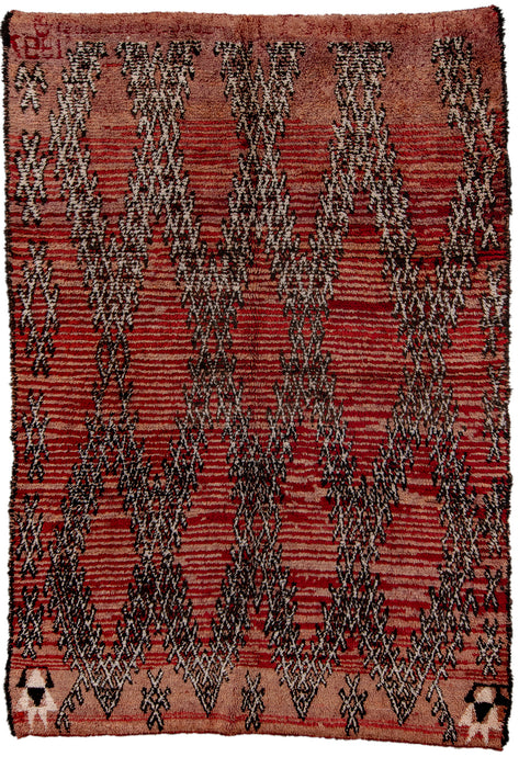 This Moroccan rug was woven in the High Atlas mountains of Morocco during the 20th century.  It features a barbed wire lattice diamond design on variegated purple ground. The deep contrast of the variegation gives it an organic striping. The lattice is flanked by evil eyes symbols on either side and the date 