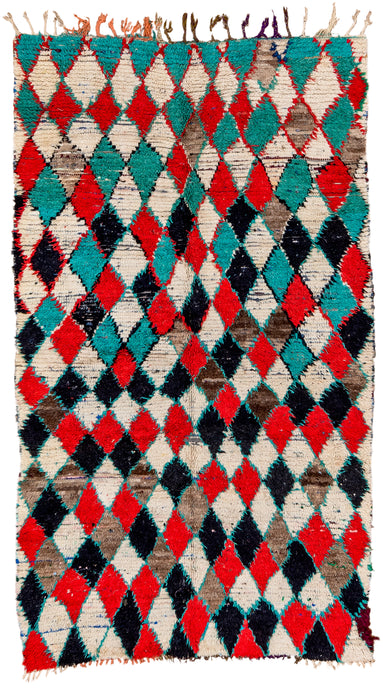 This Boucherouite rug was handwoven in Morocco during the end of the 20th century.   Boucherouite rugs are made using recycled fabrics, giving them their distinctive multicolor and shaggy pile. This funky rug features a diamond checkerboard pattern in black, ivory, red and turquoise.  The lovely free flowing nature is accentuated by the changing proportions of the diamonds and uneven use of the vibrant tones (especially the turquoise!) 