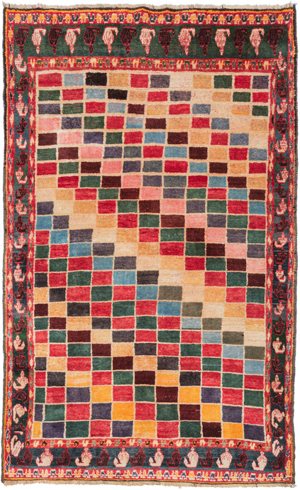 This Gabbeh rug was handwoven in Southern Iran during the middle of the 20th century.  It features alternating stepped rows of polychrome squares that travel on the diagonal creating a geometric rainbow effect. With a main border of light and dark boteh on a wonderful green ground framed by minor borders of alternating 