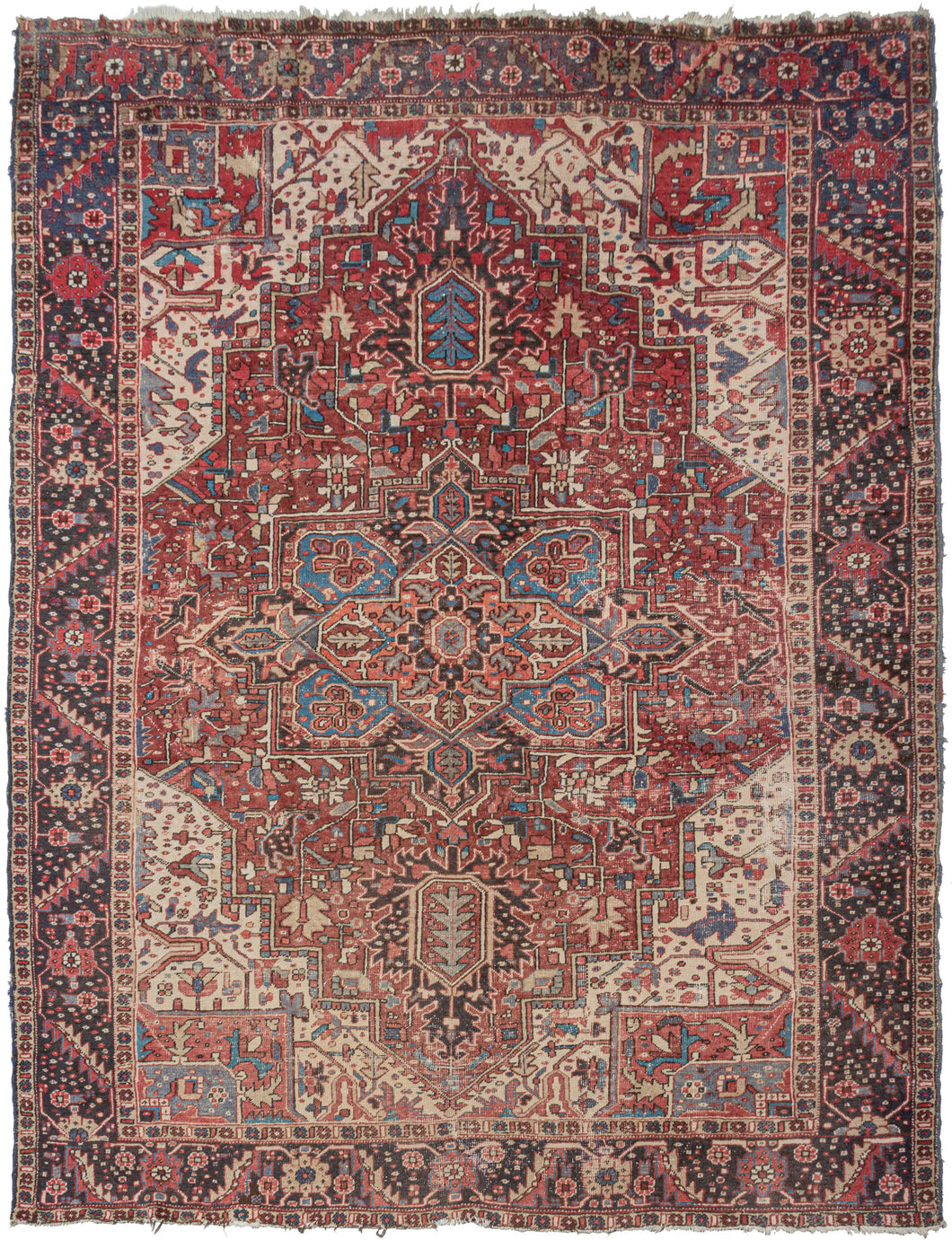 This Heriz rug was handwoven in Northwest Iran during the middle of the 20th century.  This classic Heriz features a geometric central medallion on a faded red ground. The four ivory cornices brighten the composition and the aubergine border adds something a little different .   In good condition, with visible wear throughout which gives the rug an edgy feel.