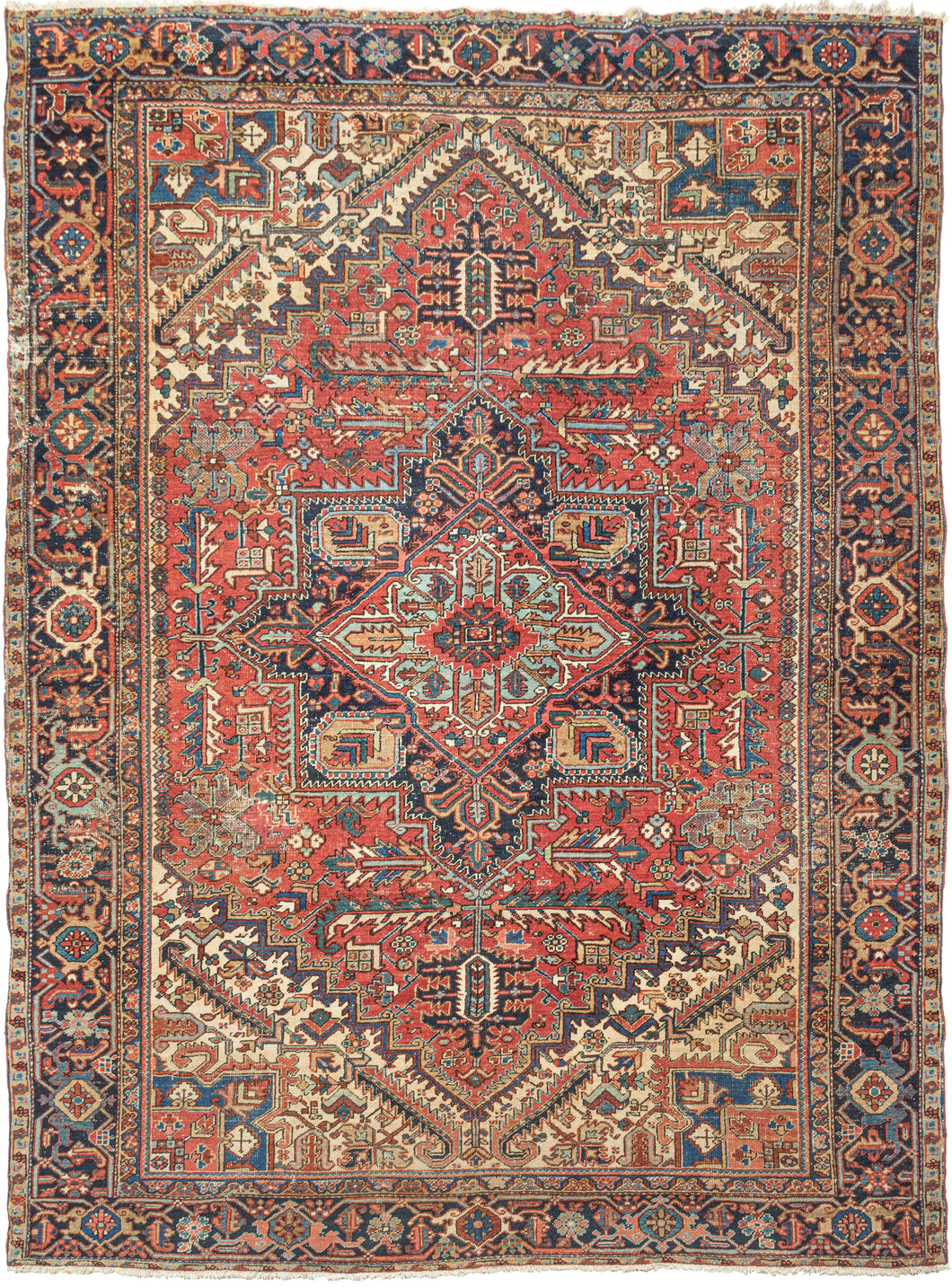 This ﻿Heriz rug was handwoven in Northwest Iran during the second quarter of the 20th century.  This classic Heriz features a geometric central medallion on a madder red ground. The four cornices loosely mirror the field design in a different color combination with the use of ivory working to light the composition. The inclusion of marled yarn palmettes  and 