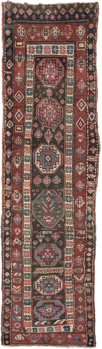 NW Persian antique Kurdish learning runner featuring a central field of disproportionate octagonal medallions with strips of random patterning running along the length of the rug. The primary colors displayed are black, copper, ivory, light blue, and pink/purple. What makes this piece truly special is the unmistakable human touch.
