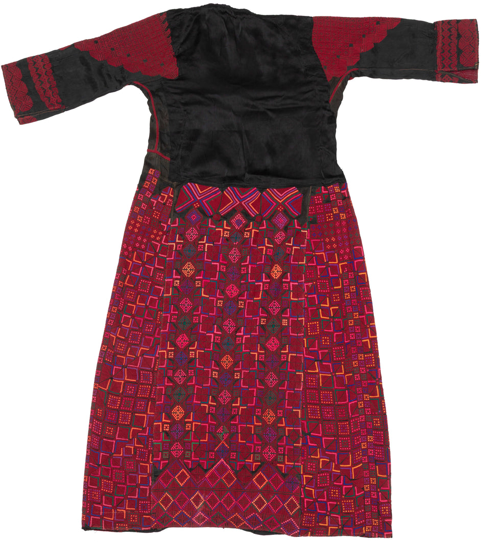 A bold and finely worked Palestinian thobe from the Ramallah–al-Bireh region, distinguished by its saturated red embroidery set against a dark ground and its highly structured, architectural composition.

Dense geometric embroidery covers the skirt, sleeves, and shoulders in tightly organized grids of stepped squares, lozenges, and subdivided diamonds. Vertical embroidered panels frame the body, while the chest features a strong triangular yoke above three square motifs, a characteristic layout associated w